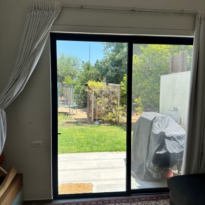 חלון זכוכית גדול עם וילון לבן בצד