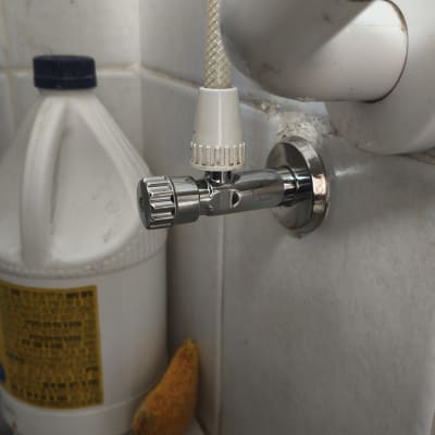 ברז מים מותקן על קיר עם בקבוק חומר ניקוי