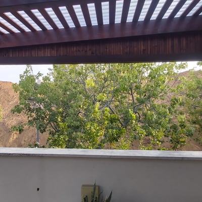 פרגולה מעץ עם צמחייה ירוקה ברקע