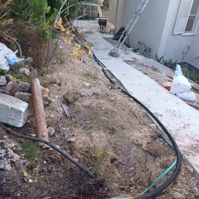 צינורות פלסטיק מונחים בתעלה ליד מבנה