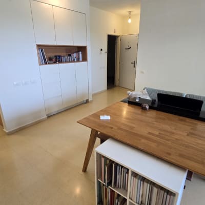 חדר עם שולחן עץ, מדף ספרים, ותאורה פשוטה