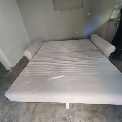 ספה נפתחת בצבע בהיר על רצפת אריחים