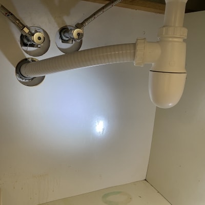 צינור ניקוז לבן מתחת לכיור עם חיבורים