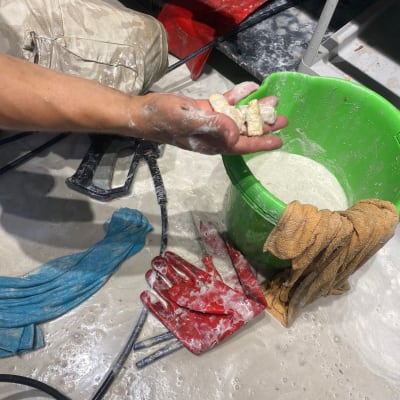 ידיים עם כפפות אדומות, דלי ירוק, כלים על הרצפה