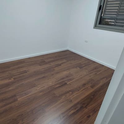 רצפת פרקט עץ כהה בחדר ריק עם קירות לבנים