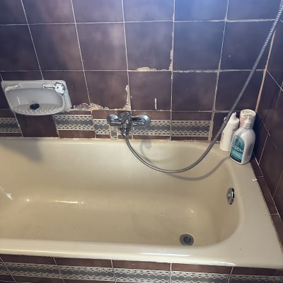 אמבטיה עם אריחים פגומים וקיר מתקלף