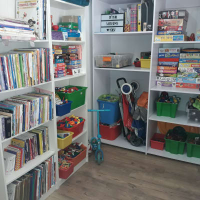 מדפים עם ספרים, משחקים וצעצועים מאורגנים בקופסאות