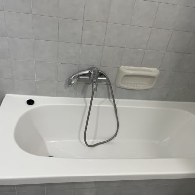 אמבטיה לבנה עם ברז ומחזיק סבון על קיר אריחים