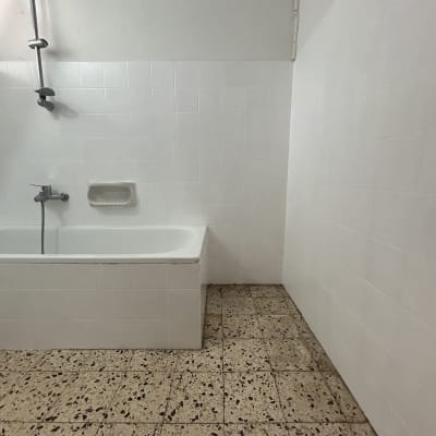 חדר אמבטיה עם אריחים לבנים ורצפת קרמיקה