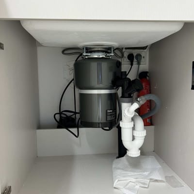 כיור עם מטחנת אשפה וצנרת מתחת לכיור