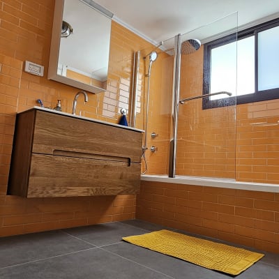 חדר אמבטיה עם אריחים כתומים, כיור עץ ומקלחת זכוכית