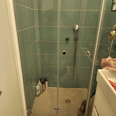 מקלחון עם בקבוקי שמפו וסבון על הרצפה