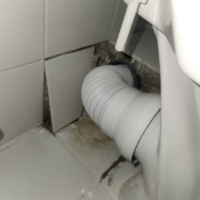 צינור פלסטיק מחובר לאסלה עם אריחים שבורים