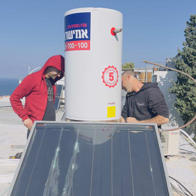 שני אנשים מתקינים דוד שמש על גג