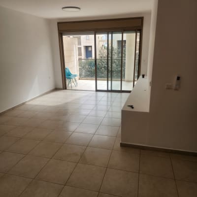 רצפה נקייה עם חלון גדול וכיסא במרפסת