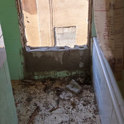 חלון פתוח עם קיר מתקלף ופטיש על הרצפה