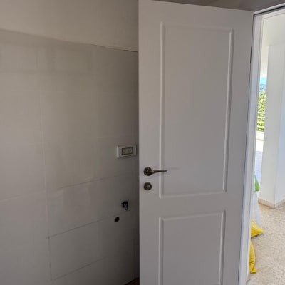 דלת לבנה פתוחה בחדר עם קיר לבן ורצפת אריחים