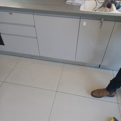 מטבח עם ארונות, כיור וכלי ניקוי על השיש