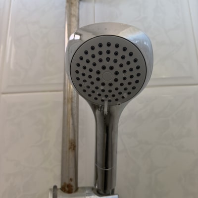 ראש מקלחת עם צינור חלוד על קיר