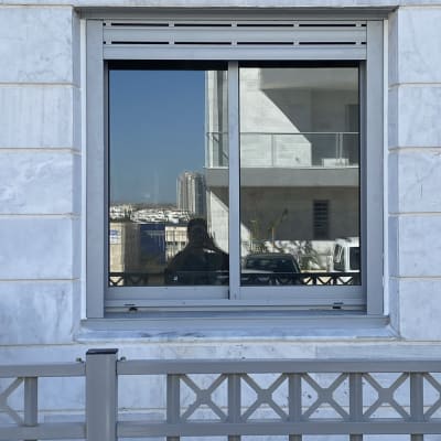חלון אלומיניום עם מסגרת אפורה על קיר שיש