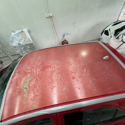 גג רכב אדום עם קילופי צבע וסרט דבק אפור