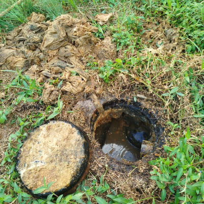 בור ביוב פתוח עם מכסה מונח בצד