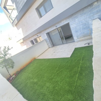 דשא סינתטי בגינה ליד בניין מגורים