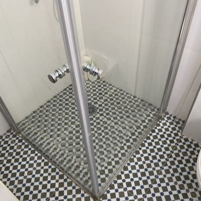 מקלחון עם רצפת אריחים מעוצבת וברזים כסופים