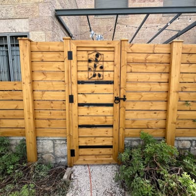 שער עץ עם עיטור מתכת, גדר עץ, צמחייה מסביב