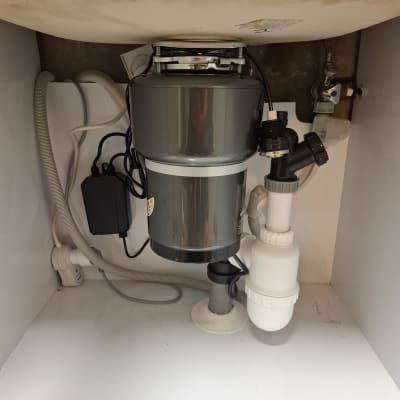 מתקן טוחן אשפה מתחת לכיור עם צינורות וחיבורים