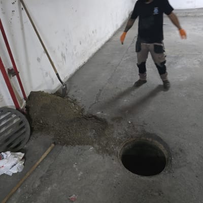 עבודת ניקוי סביב פתח ביוב עם כלי עבודה ואדם