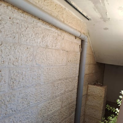 צינור פלסטיק אפור מותקן על קיר אבן