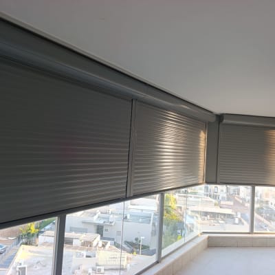תריסי גלילה חשמליים מאלומיניום בסגירת מרפסת בדירה
