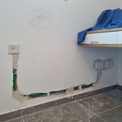 שקעי חשמל על קיר עם חוטים ירוקים חשופים