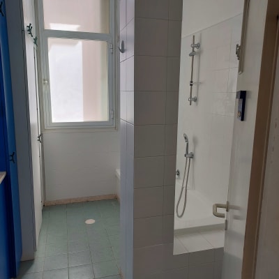 חדר אמבטיה עם אריחים לבנים, מקלחת ואור תלוי