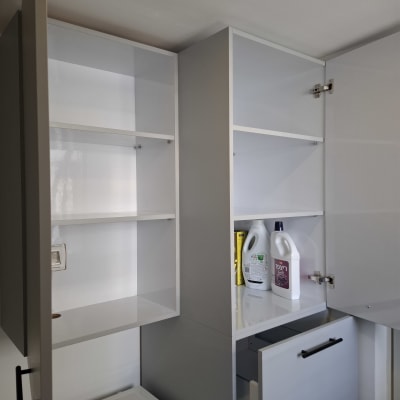 ארונות מטבח פתוחים עם מדפים ריקים וחומרי ניקוי