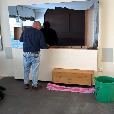 אדם עובד על התקנת מראה גדולה בחדר