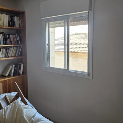 חלון עם תריסים בחדר שינה עם מדף ספרים