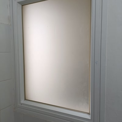 חלון זכוכית חלבית במסגרת לבנה