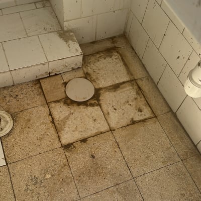 רצפת אריחים עם ניקוז, צינור לבן, סימני לכלוך