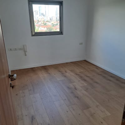 חדר ריק עם רצפת פרקט וחלון עם נוף עירוני