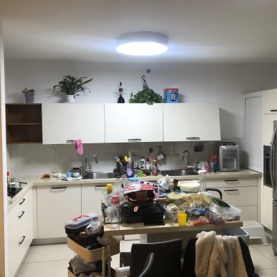 מטבח עם ארונות לבנים, כיור, מקרר וכלים על השיש