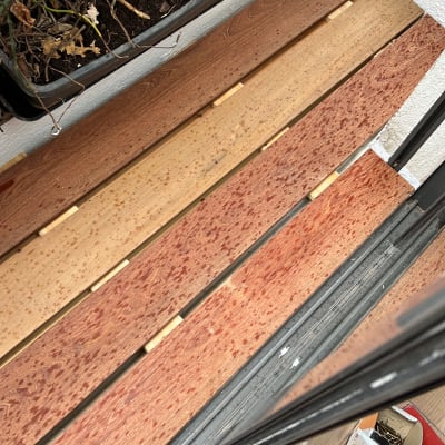 לוחות עץ וכלי עבודה על רצפה ליד עציצים