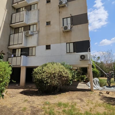 אדם צובע בניין מבחוץ עם רולר גבוה