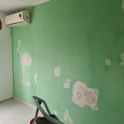 קיר ירוק עם תיקוני צבע וסולם קטן