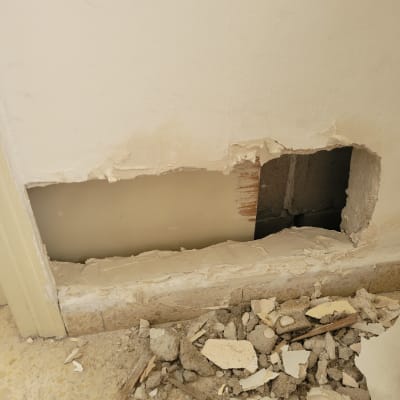 חור בקיר עם פסולת בנייה על הרצפה