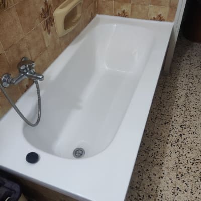 אמבטיה לבנה עם ברז מתכת וקיר אריחים חום