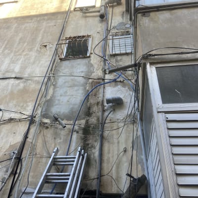 סולם מתכת ליד קיר עם צינורות וכבלים