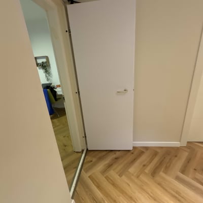 דלת לבנה פתוחה עם ידית כסופה על רצפת פרקט