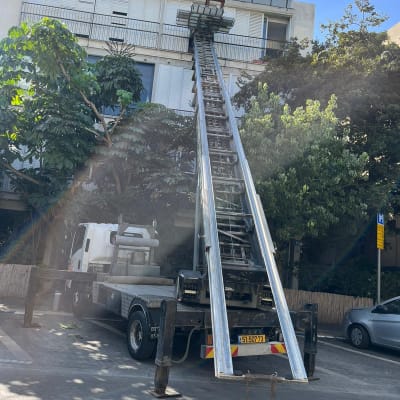 משאית מנוף הרמה סולם מתוח לכיוון מרפסת בבניין מגורים